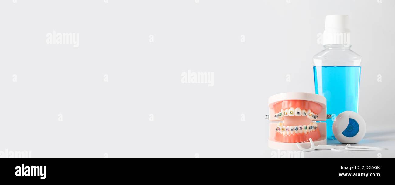 Model of jaw with braces, toothpicks, dental floss and mouth rinse on