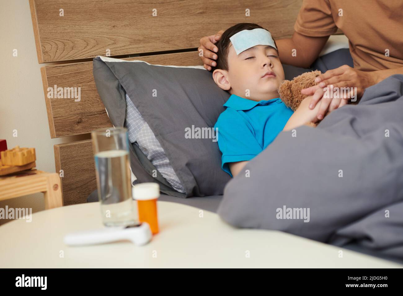 Sick child suffering from fever trying to sleep with cooling patch on