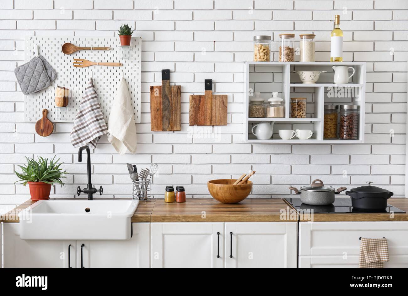 Kitchen counters with utensils and shelf unit on white brick wall Stock