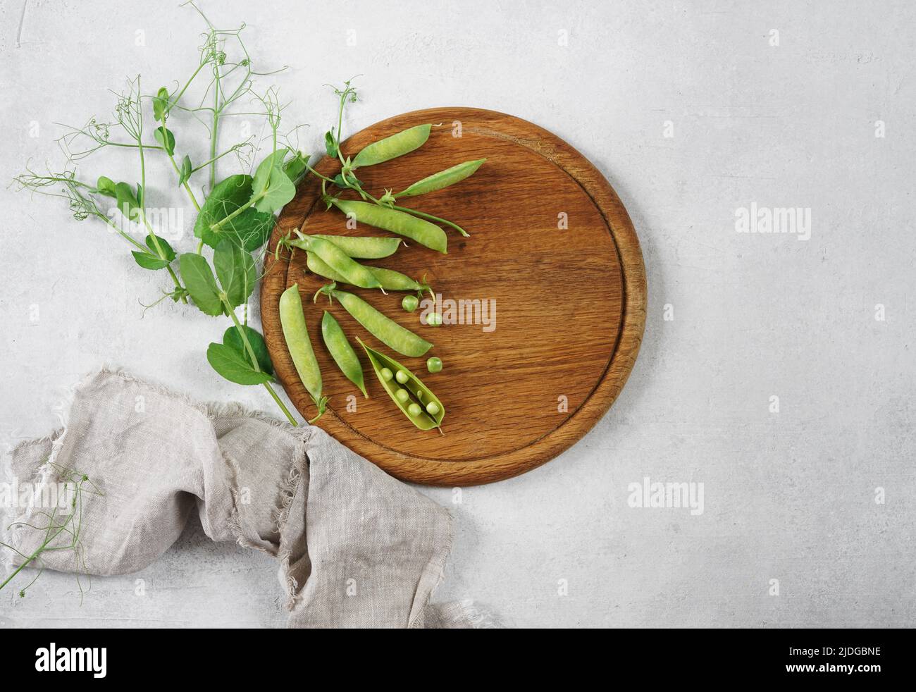 Young green peas on an round wood board on a white background Place for text. Flat lay, top view Stock Photo