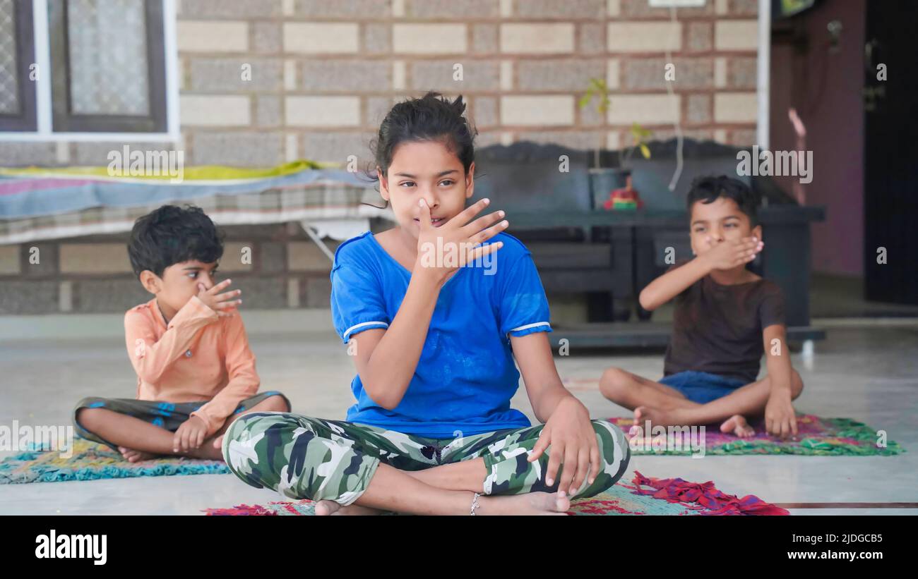 Asian kids doing yoga pose at home. Group of children doing gymnastic exercises. Stock Photo