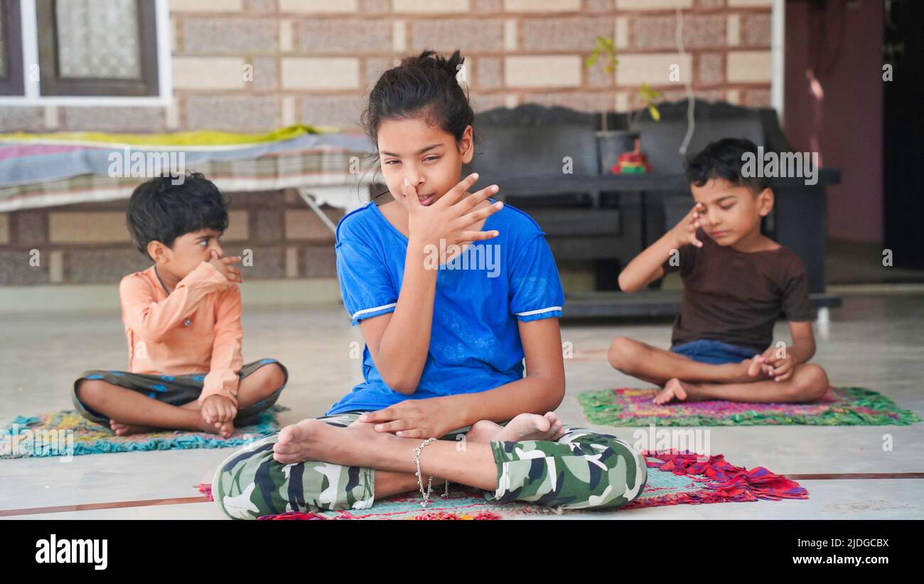 Group of children engaged in yoga at Home sitting on the mat. Stock Photo