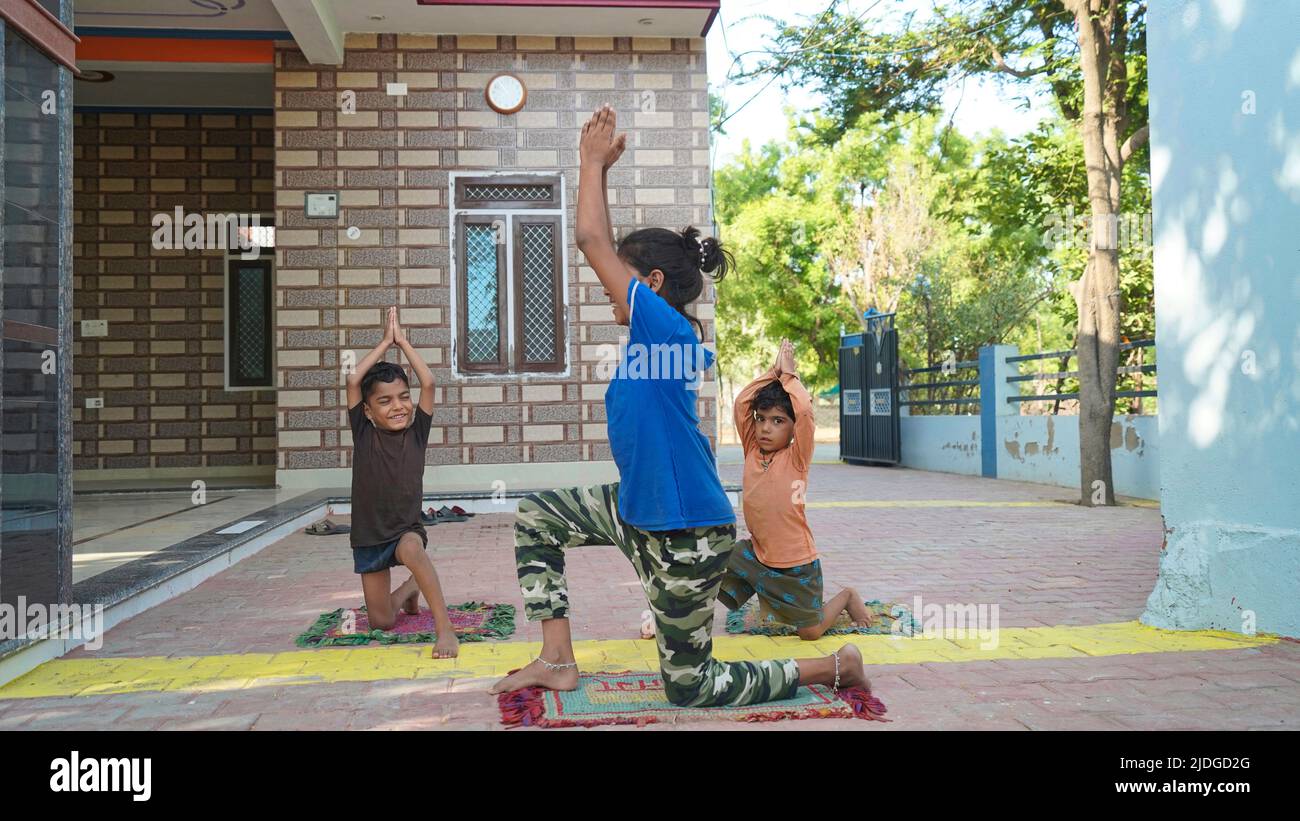 Three Indian little kids doing meditate yoga asana on roll mat at home. Stock Photo