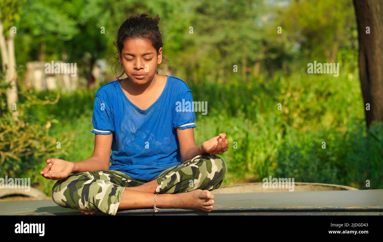 Indian Child doing exercise on platform outdoors. Healthy lifestyle. Yoga girl. Stock Photo