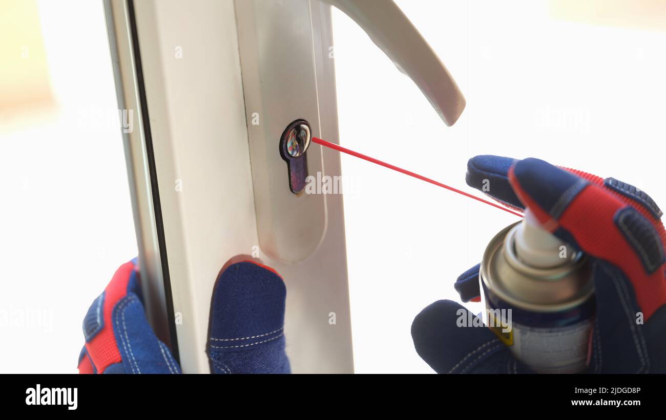 Repairman using lubricate for lock of plastic window Stock Photo