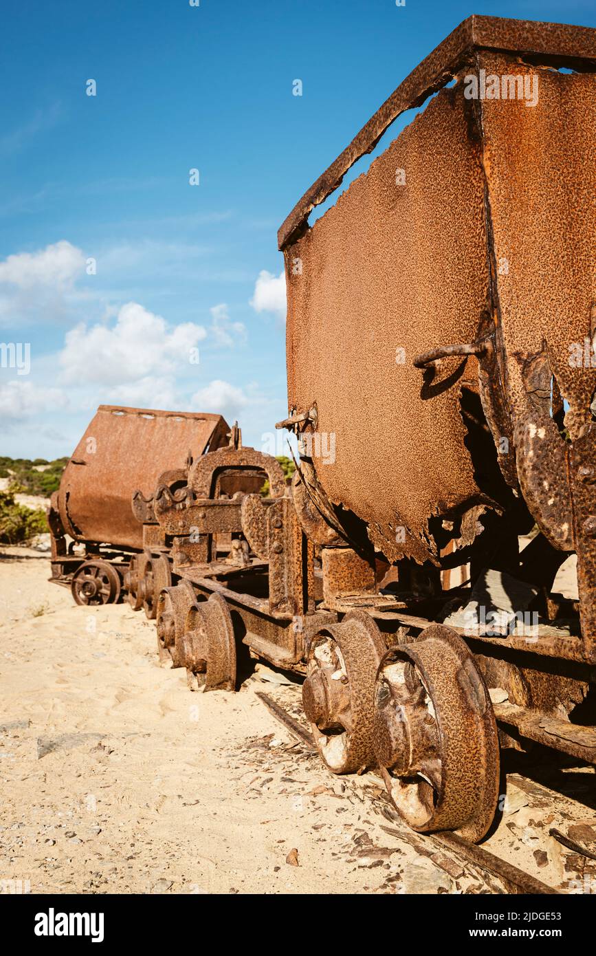 Rusty broken wagons and scrap of a railway from the lead and zinc mines to the sand dunes near the beach of Piscinas, Costa Verde, Sardinia, Italy Stock Photo