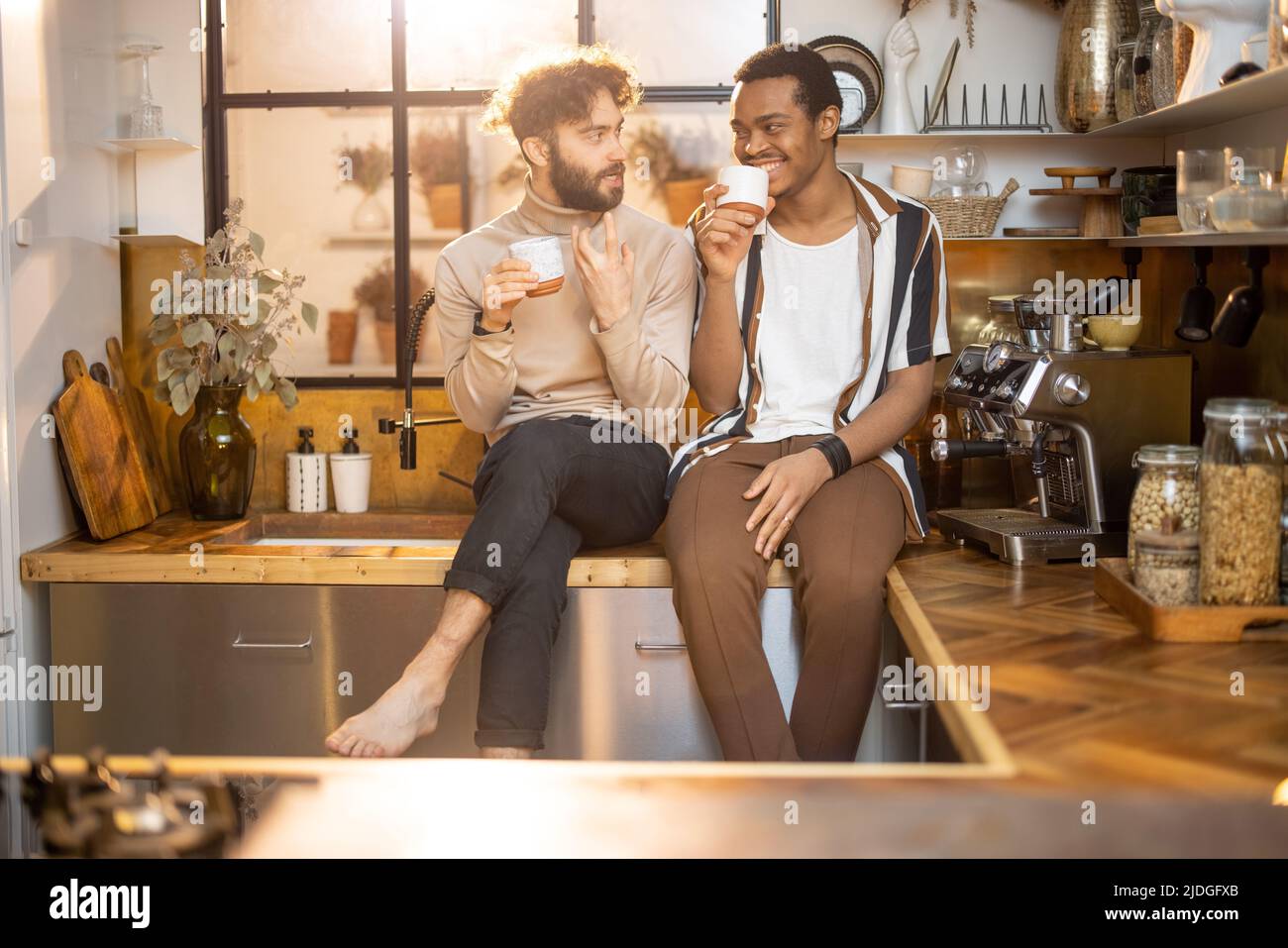 Two men talking and drinking coffee on kitchen at home Stock Photo