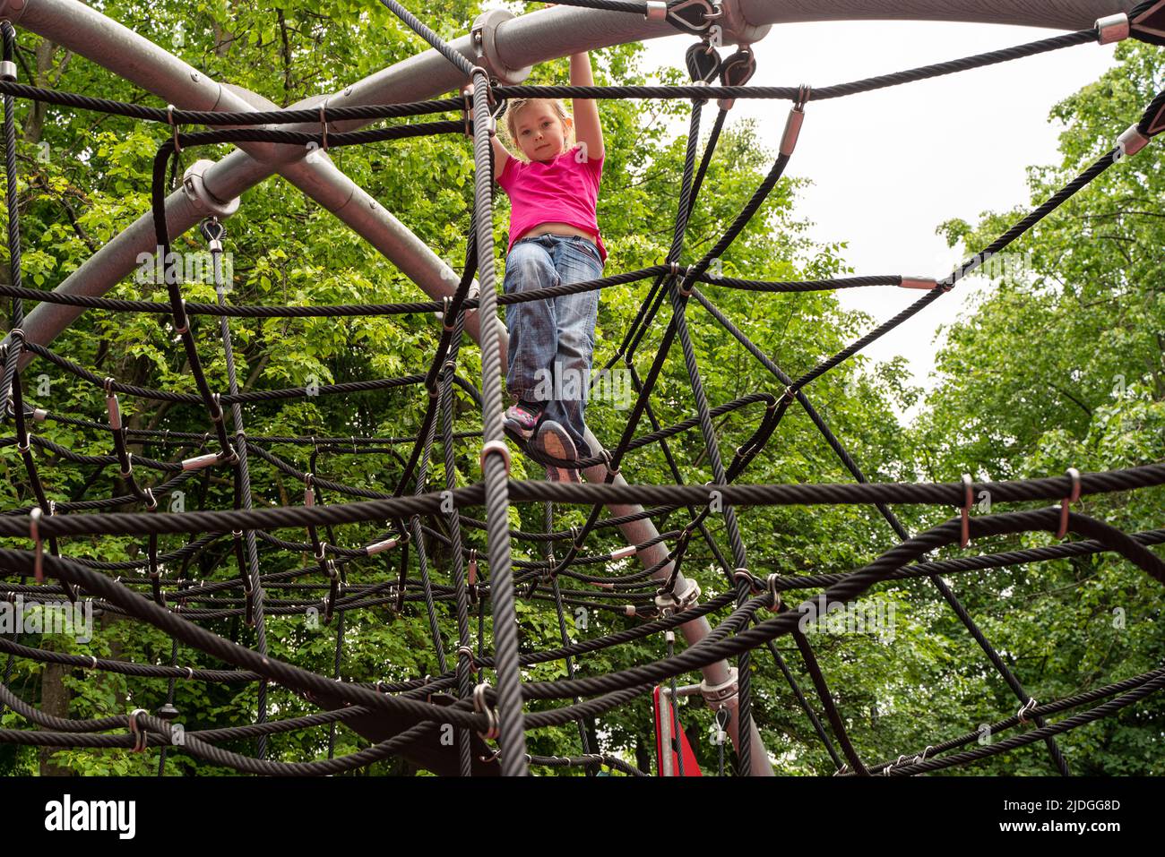 Happy teenager girl child playing in rope spider web at playground. Children. High quality photo Stock Photo
