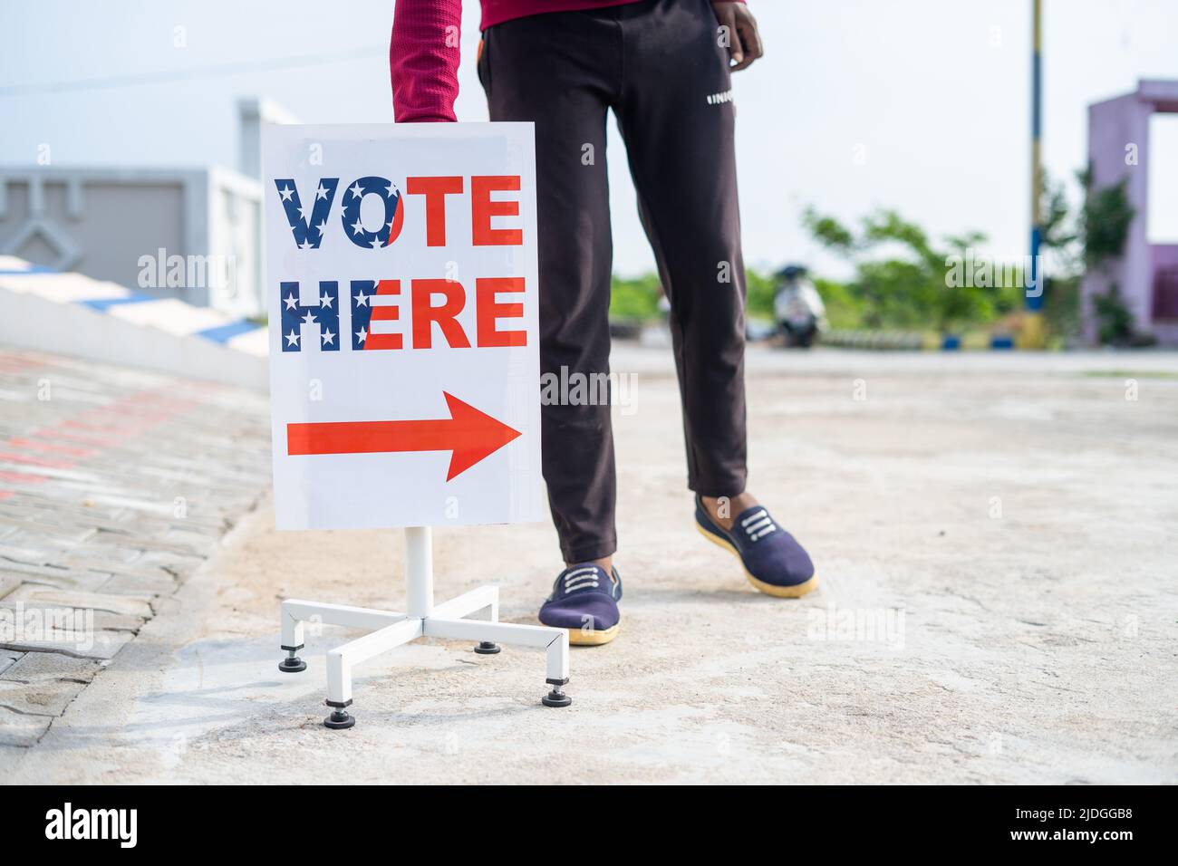 Man placing vote here sign board direction near polling booth - concept of responsibility, voting or election day and democracy Stock Photo
