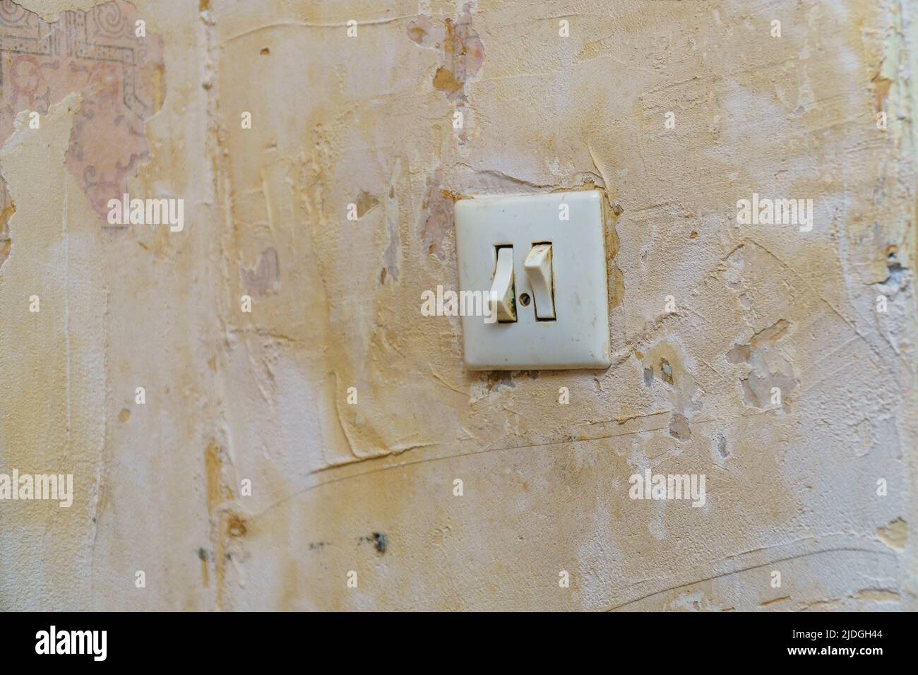 Old light switch on a shabby battered wall. Selective focus Stock Photo