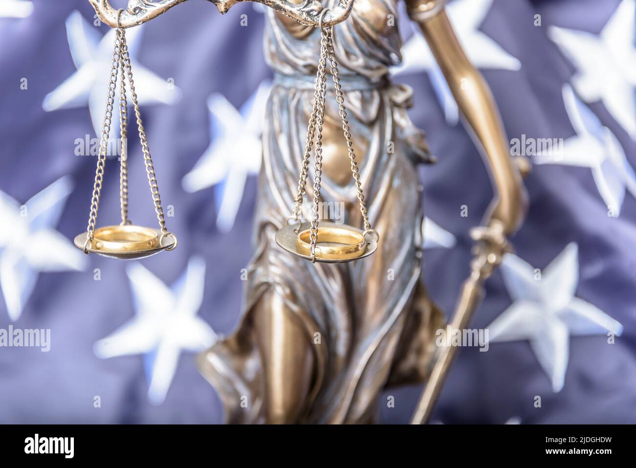 Bronze figurine of Themis holds wedding rings on scales of balance, being in foreground. Couple divorce. Stock Photo