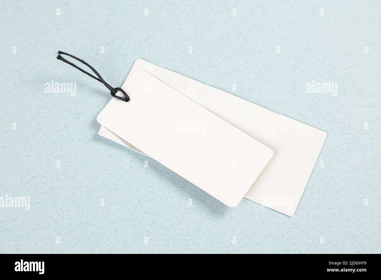 An empty white price tag lies on a gray-blue background with a soft shadow. Stock Photo
