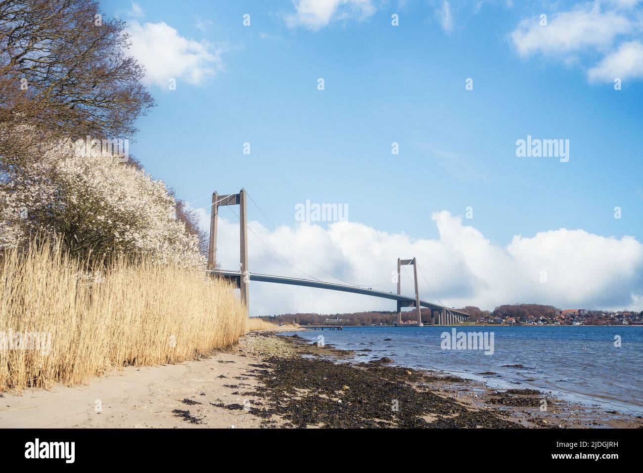 Beautiful bridge over a water passage with a sand beach and rushes along the water Stock Photo