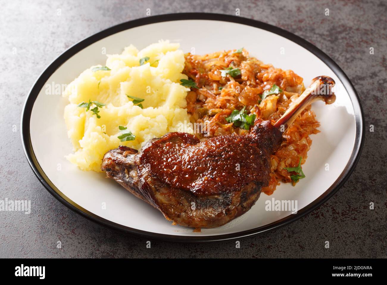 Cooked food roasted duck leg, stew cabbage, boiled potato close-up in a plate on the table. Horizontal Stock Photo