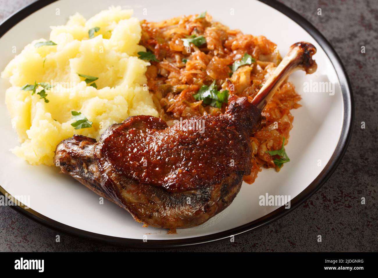 Romanian food duck leg with stewed cabbage and mashed potatoes close-up in a plate on the table. horizontal Stock Photo