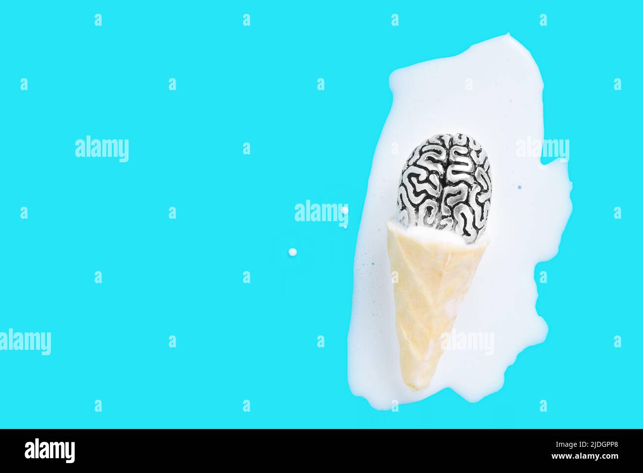 Steel copy of a human brain in melted waffle cone ice cream puddle on a blue background with copy space. Extreme hot summer concept. Stock Photo