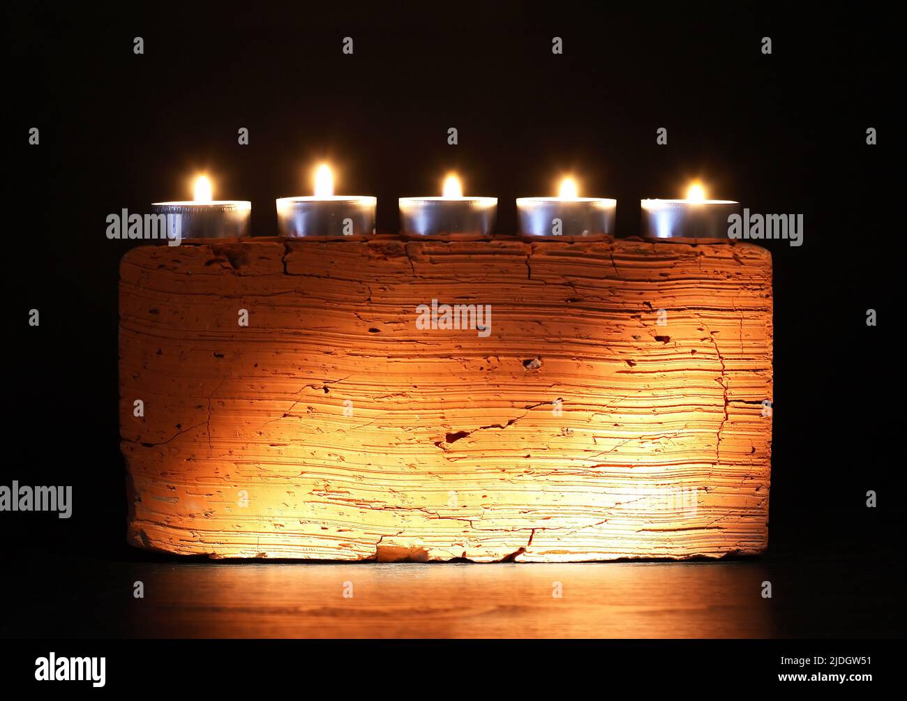 Set of lighting candles in a row against dark background Stock Photo