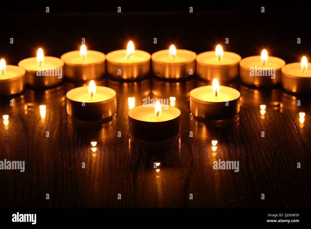 Set of flighting candles in a row against dark background Stock Photo