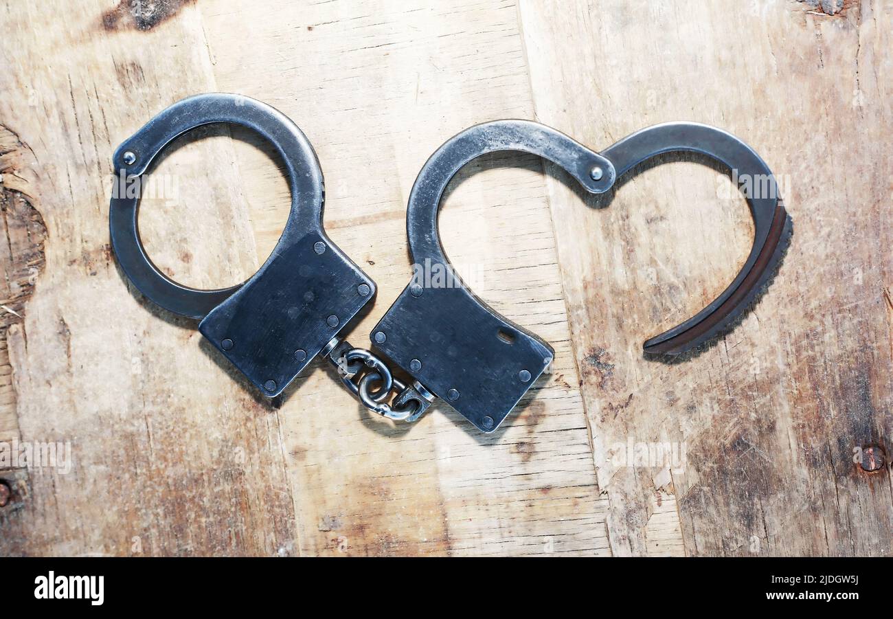 Escape concept. Old metal unfastened handcuffs on wooden background Stock Photo