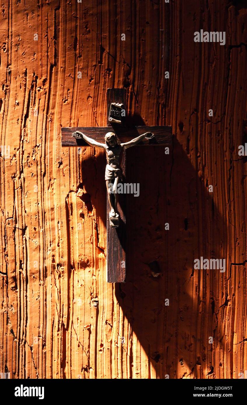 Religion symbol. Small crucifixion on brick wall under beam of light Stock Photo