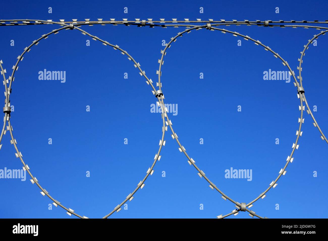 Prison symbol. Closeup of razor wire against blue sky Stock Photo