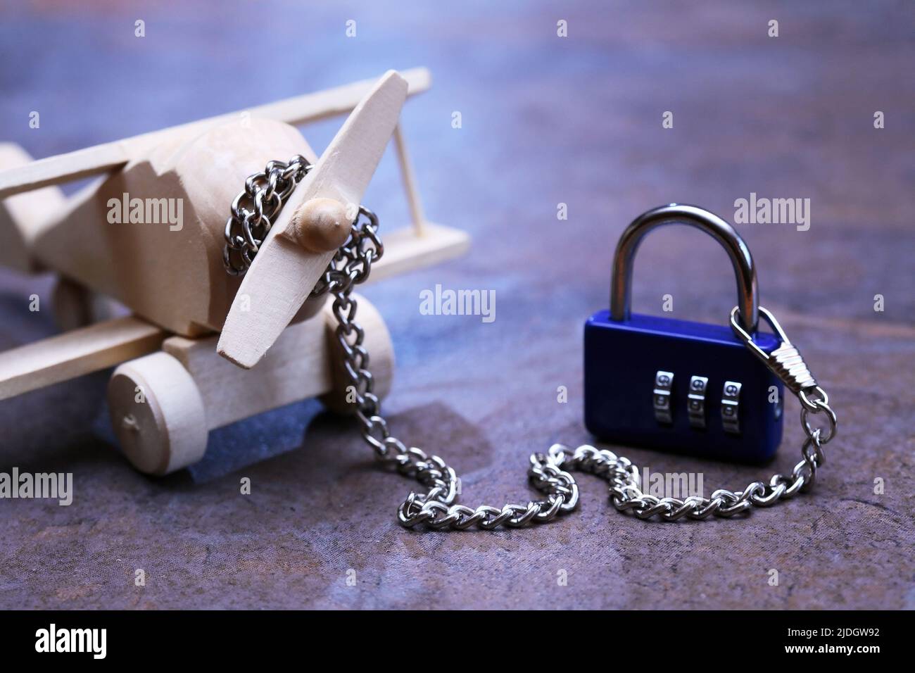 Flight ban concept. Small wooden airplane attached with metal chain Stock Photo