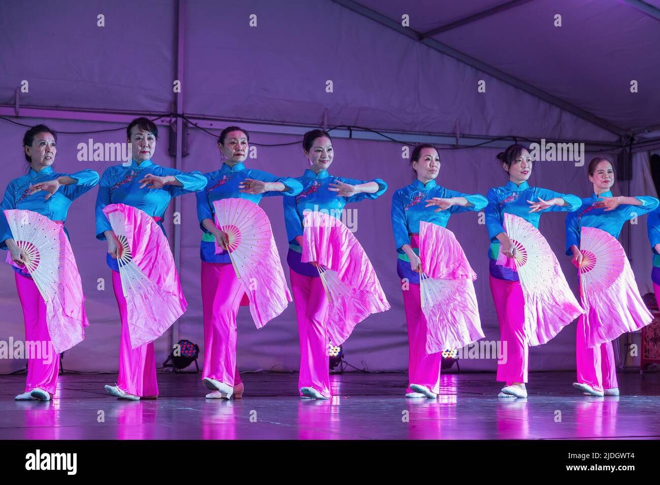 A row of Asian women performing a fan dance on stage during Moon