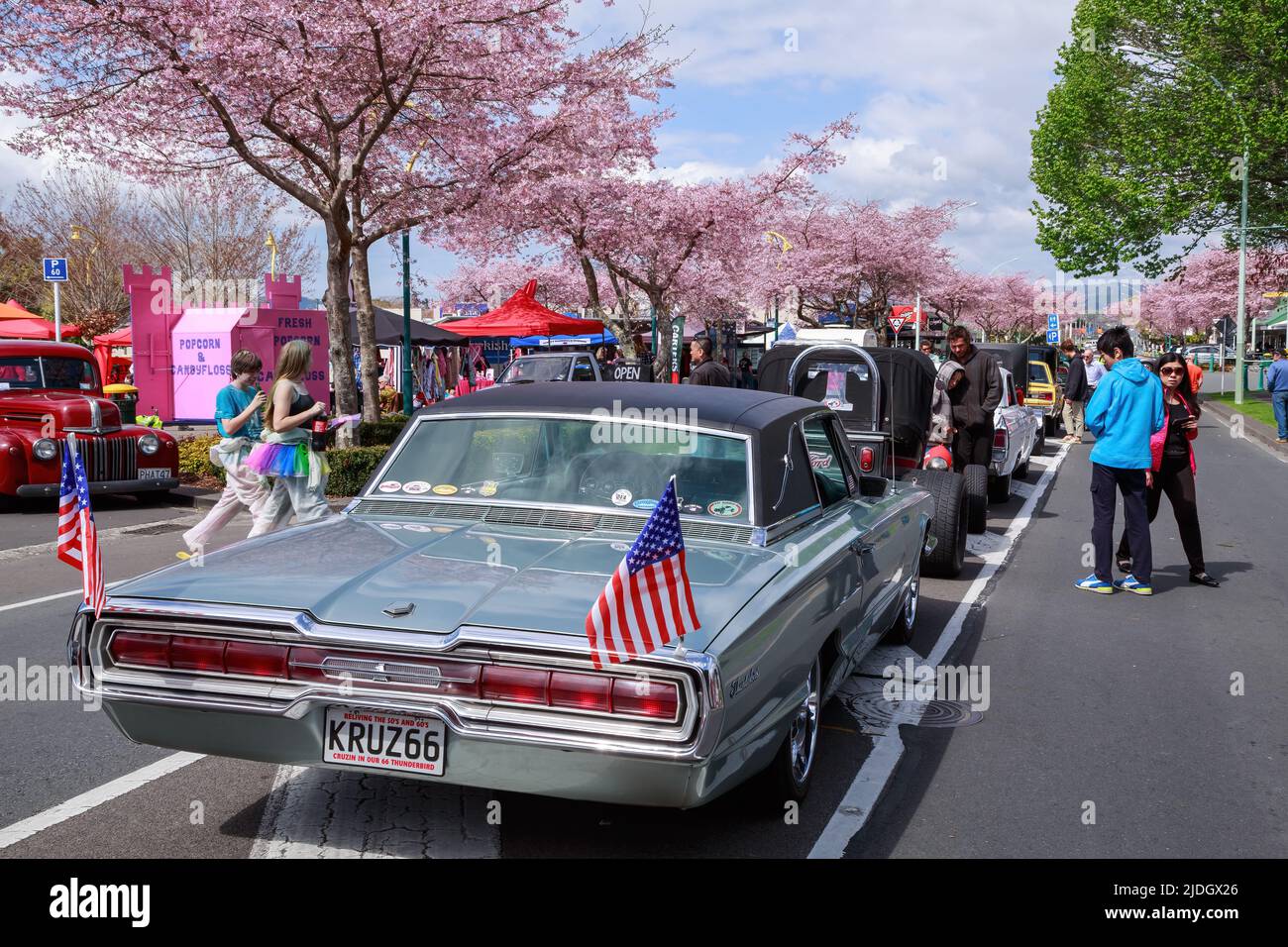 A 1966 Ford Thunderbird with American flags flying from the rear at a classic car festival. Tauranga, New Zealand Stock Photo