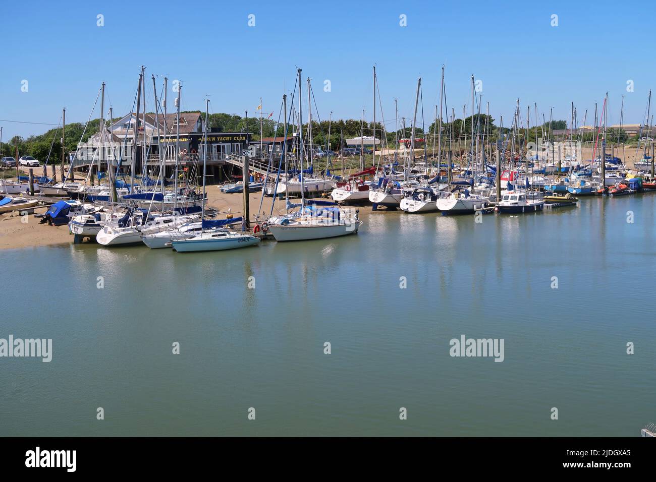 Littlempton, West Sussex, UK. Arun Yacht Club. Clubhouse sits amongst sand dunes on west bank of the River Arun. Yachts moored at floating pontoons. Stock Photo
