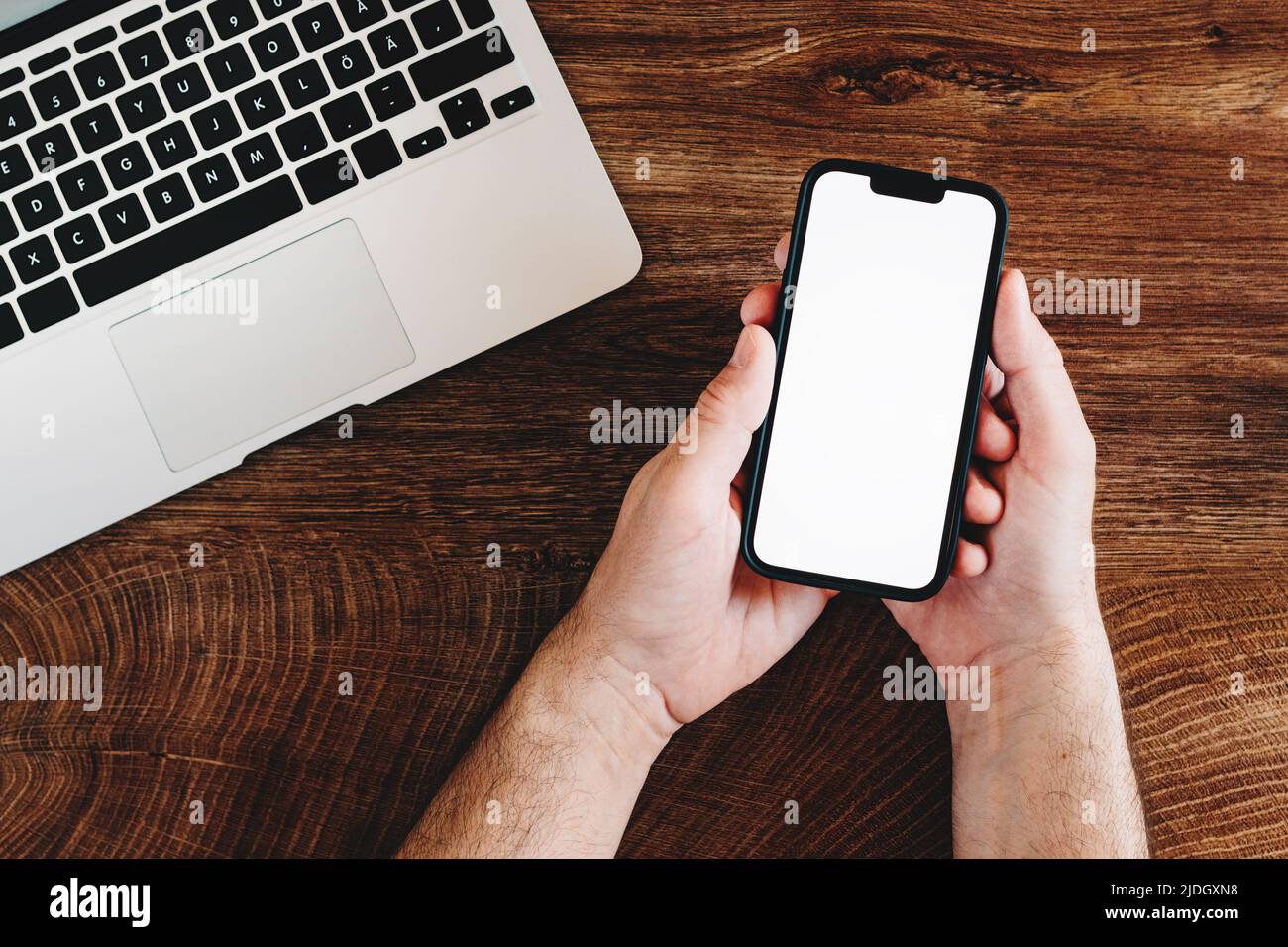 Freelancer using mobile phone with blank white mockup screen at office desk, top view Stock Photo