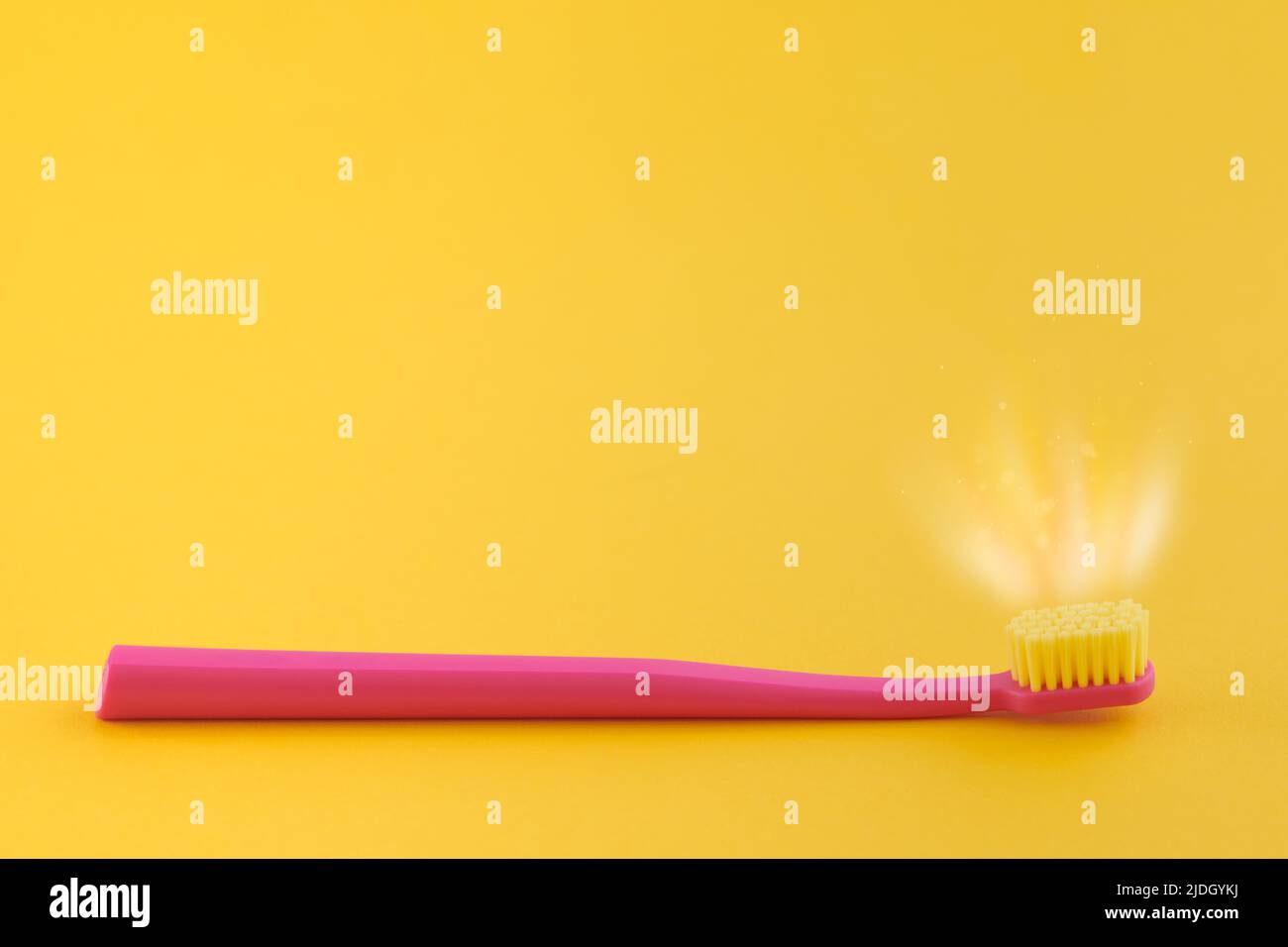 Pink toothbrush on yellow background for oral hygiene to clean teeth