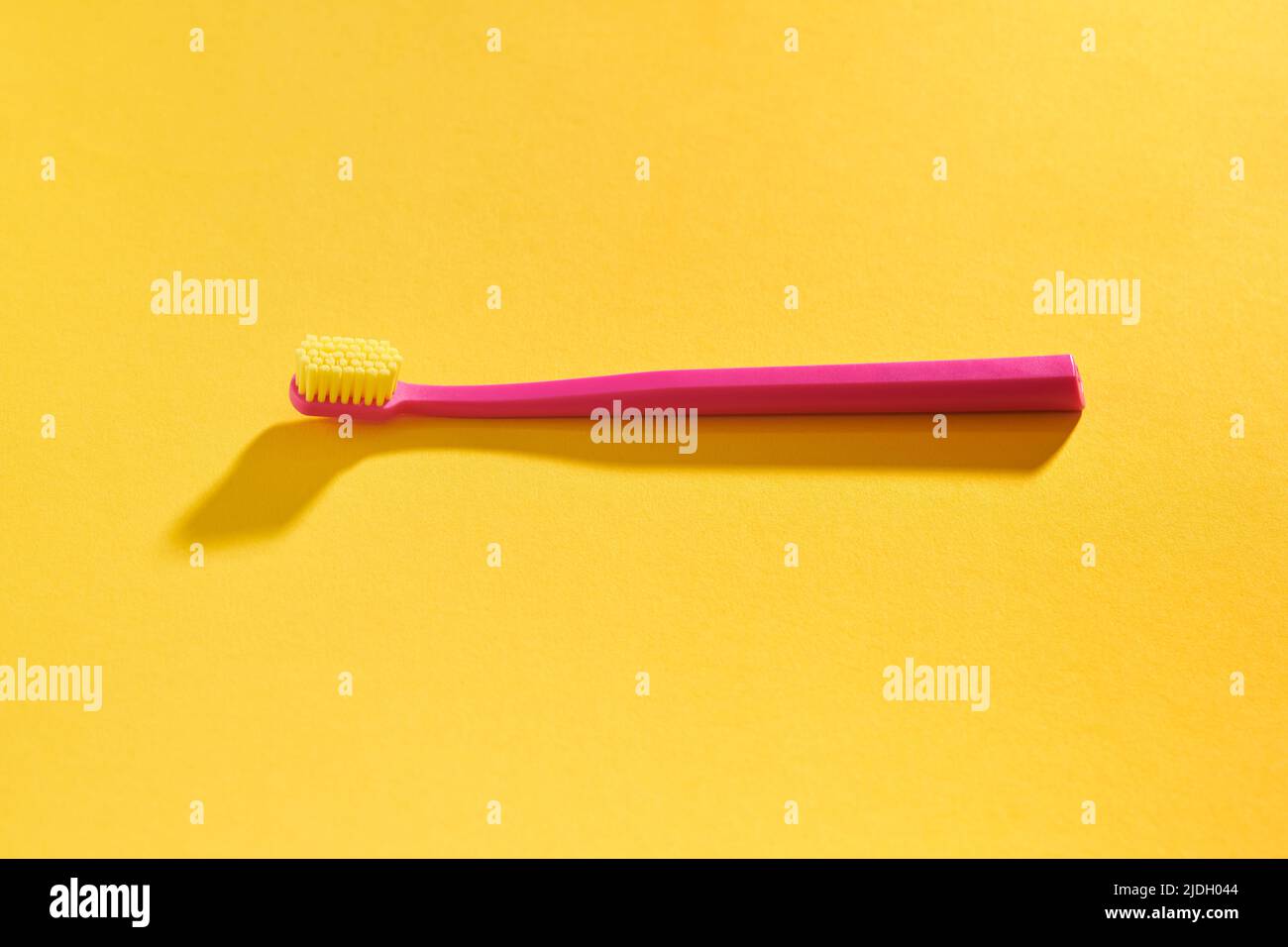 Pink toothbrush on yellow background for oral hygiene to clean teeth