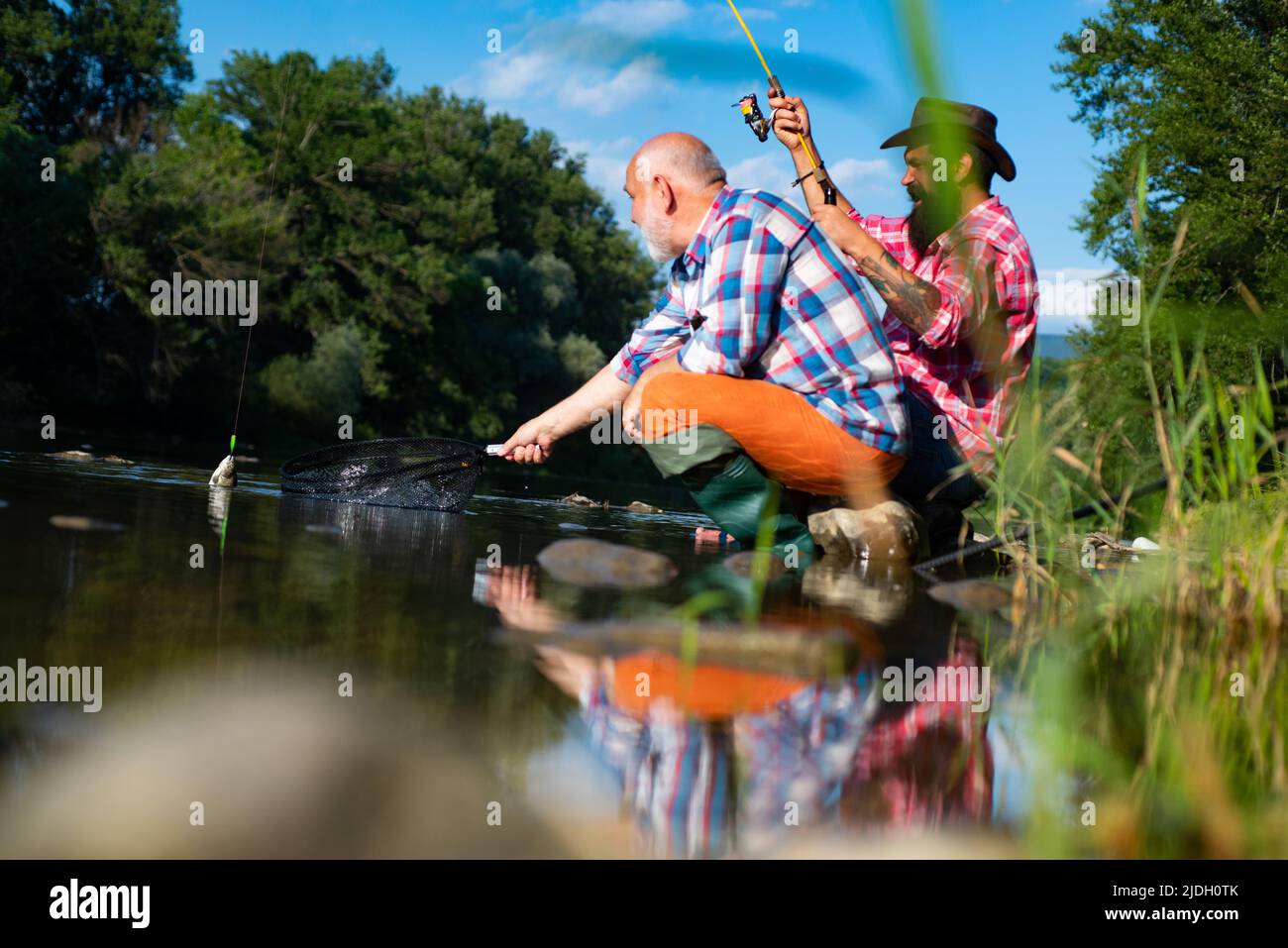 Two men friends fisherman fishing on river. Old father and son with rod ...