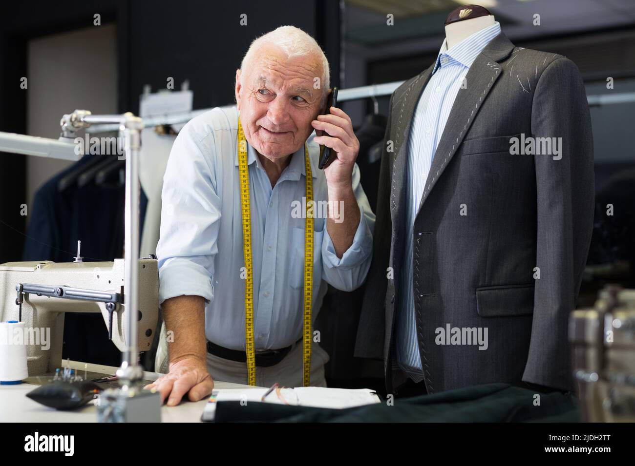 Professional tailor man talking on mobile phone and making notes in notebook Stock Photo