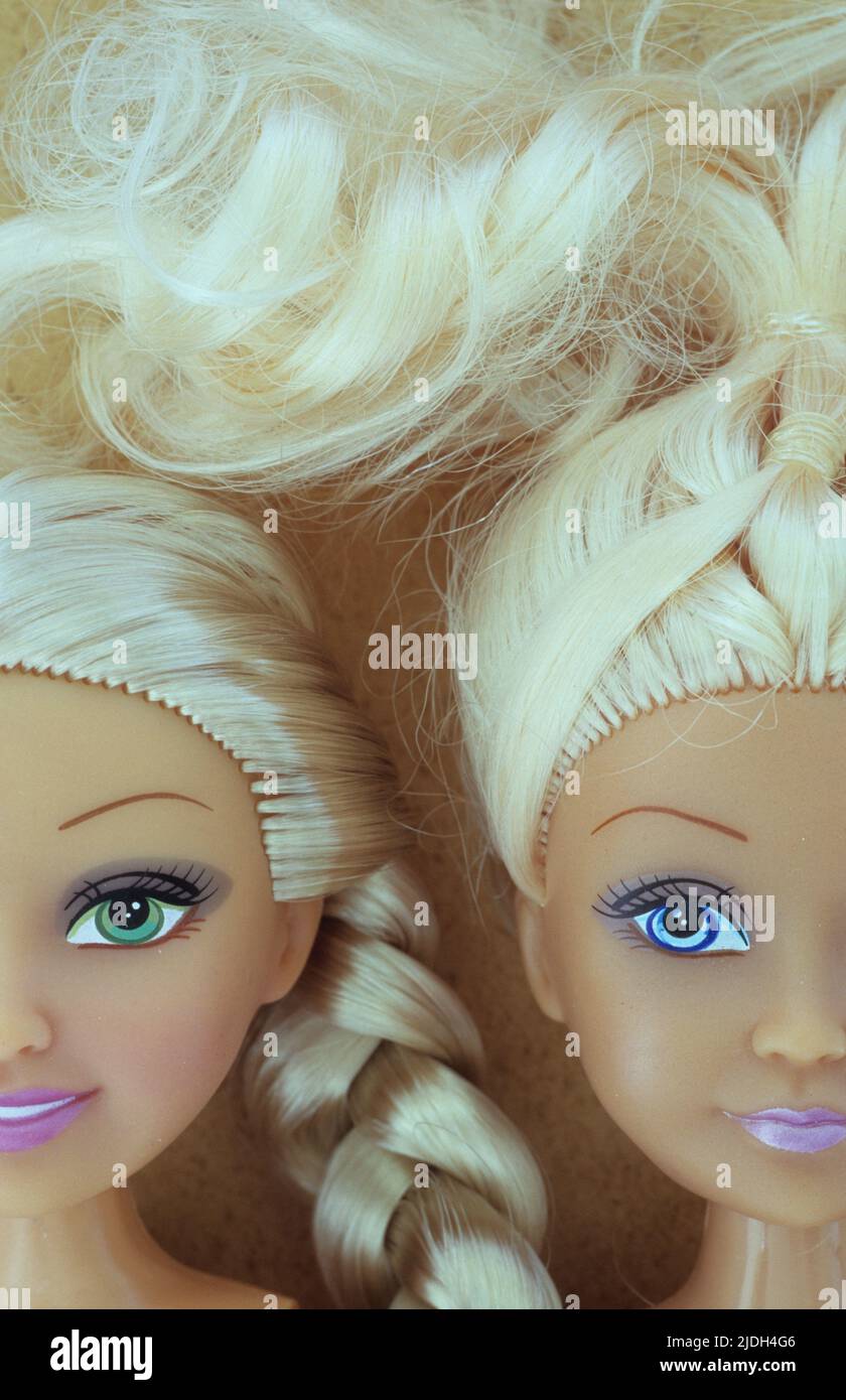 Heads of two contemporary women dolls with stereotypical big eyes and long blonde hair lying close together Stock Photo