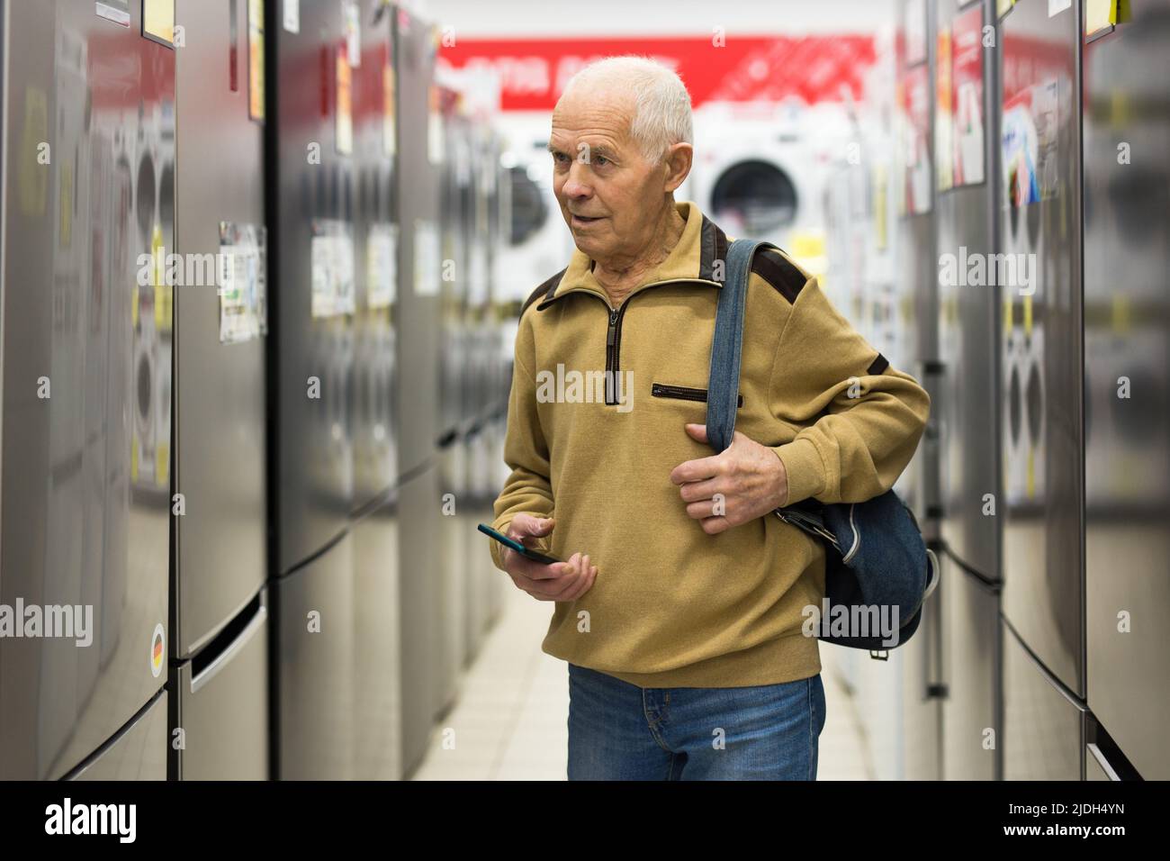 senor man pensioner buying fridge in showroom of electrical appliance store Stock Photo
