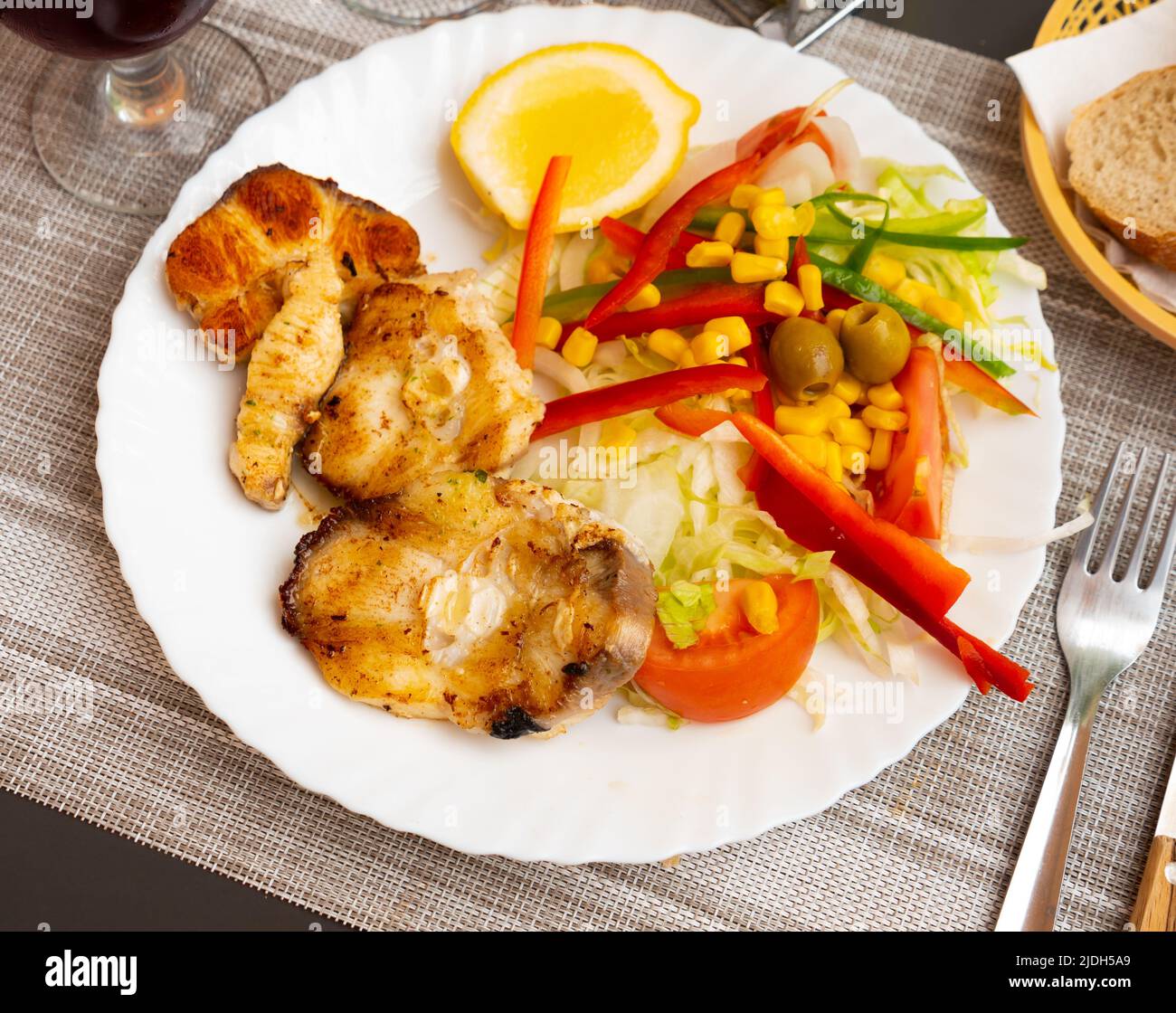 Oven baked hake with vegetable garnish Stock Photo
