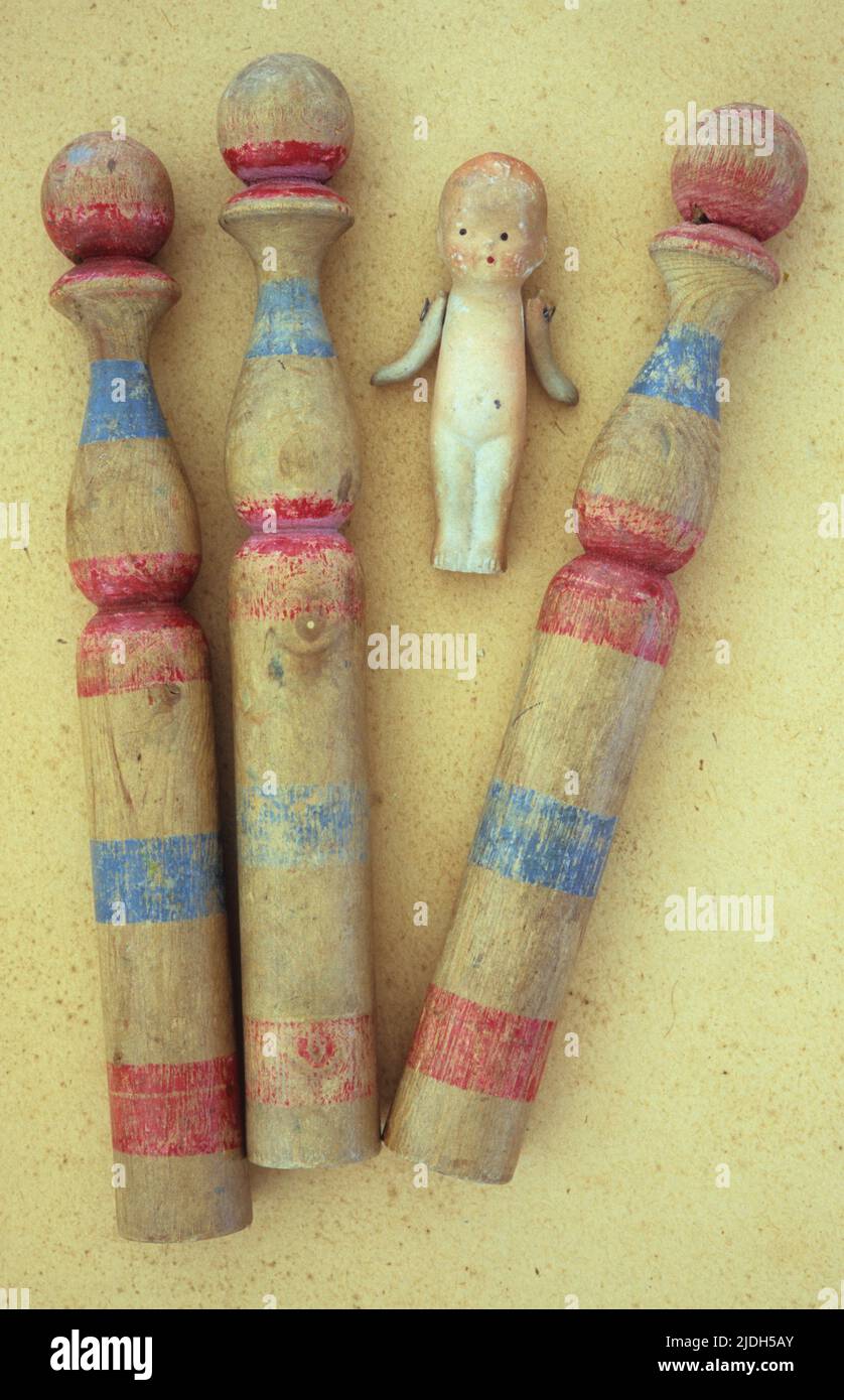 Three vintage childrens wooden skittles with scuffed blue and red painted stripes lying on antique paper with bisque doll Stock Photo Alamy