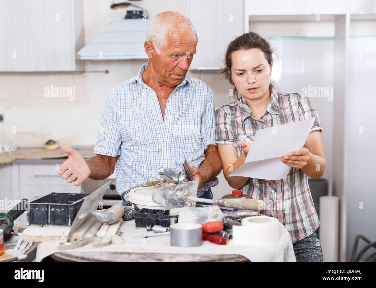 Perplexed woman and senior man with mixer tap and paper Stock Photo - Alamy