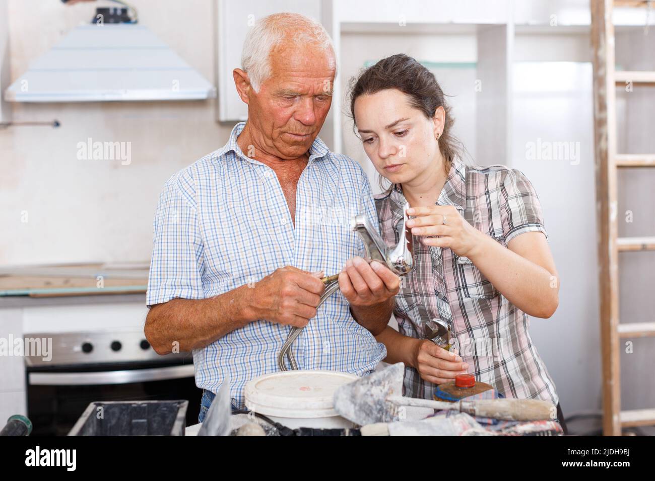 Woman and elderly father discussing installing faucet Stock Photo