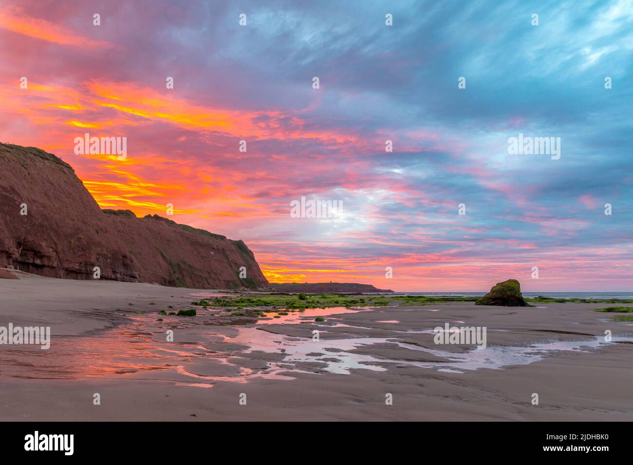 Sunrise over cliffs and beach at low tide, Orcombe Point, South Devon. Stock Photo