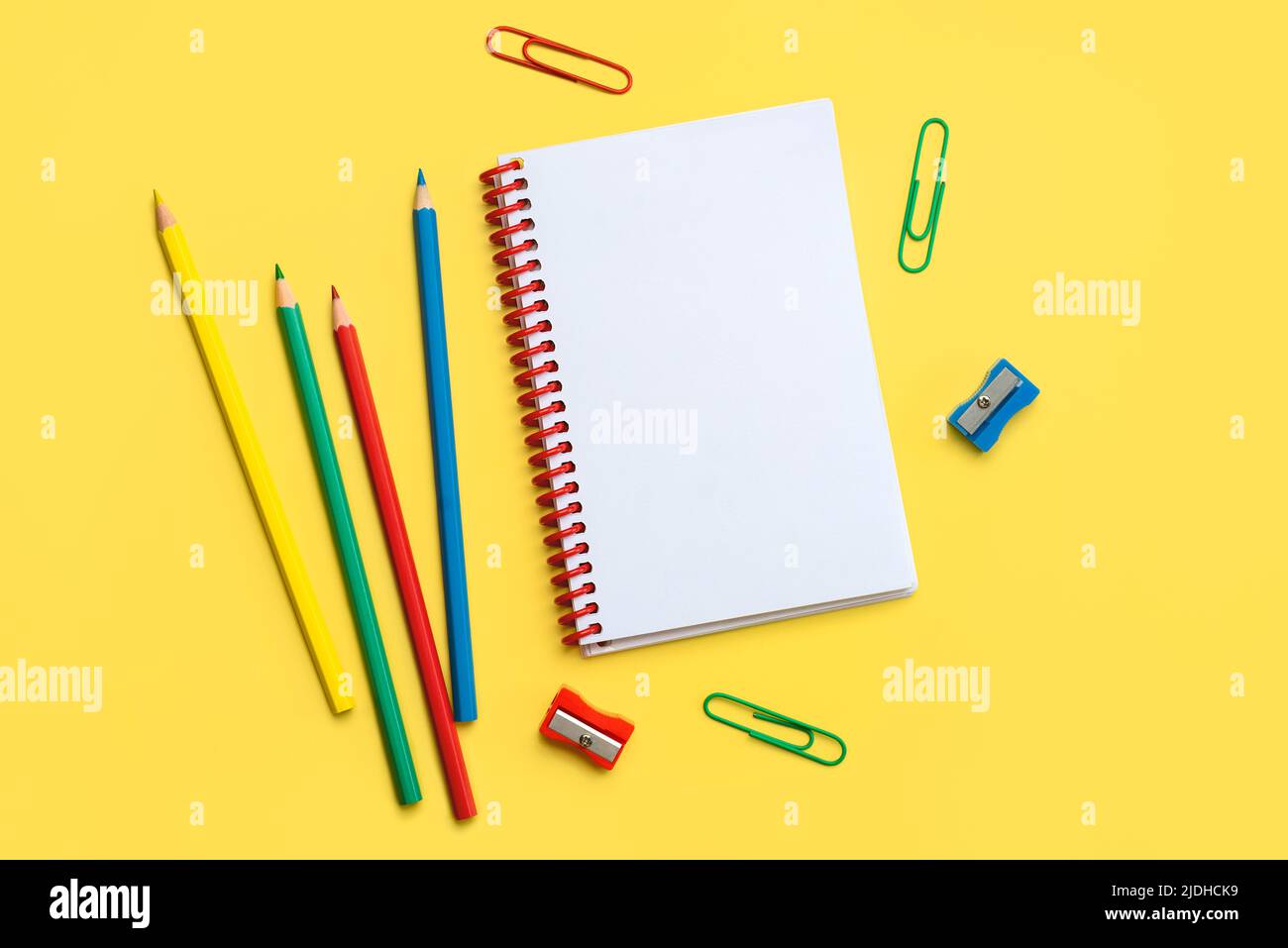 Top view of school supplies and spiral notepad with space for text on yellow background. Back to school concept Stock Photo