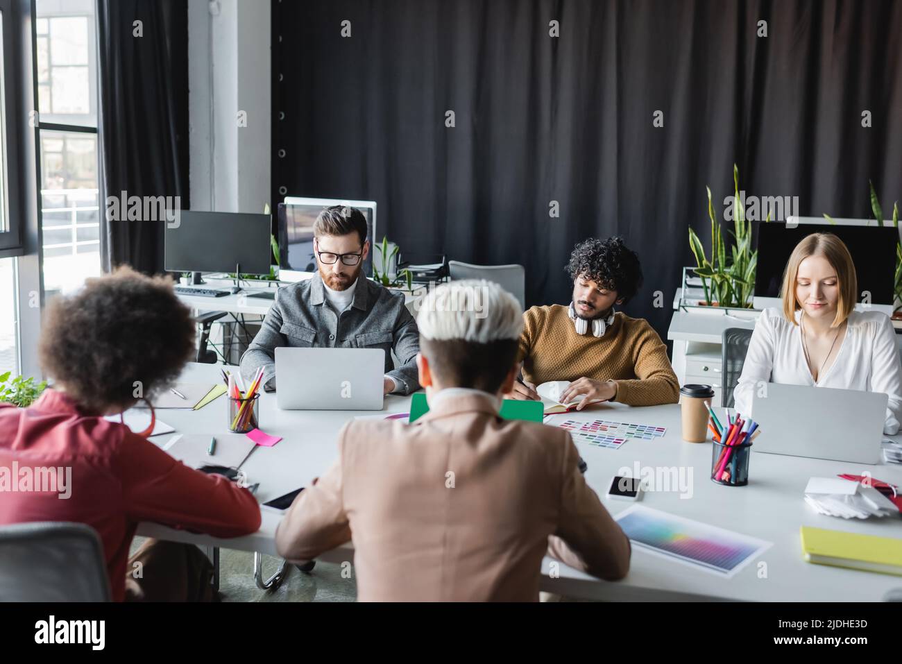 multicultural advertising managers working near laptops in meeting room ...