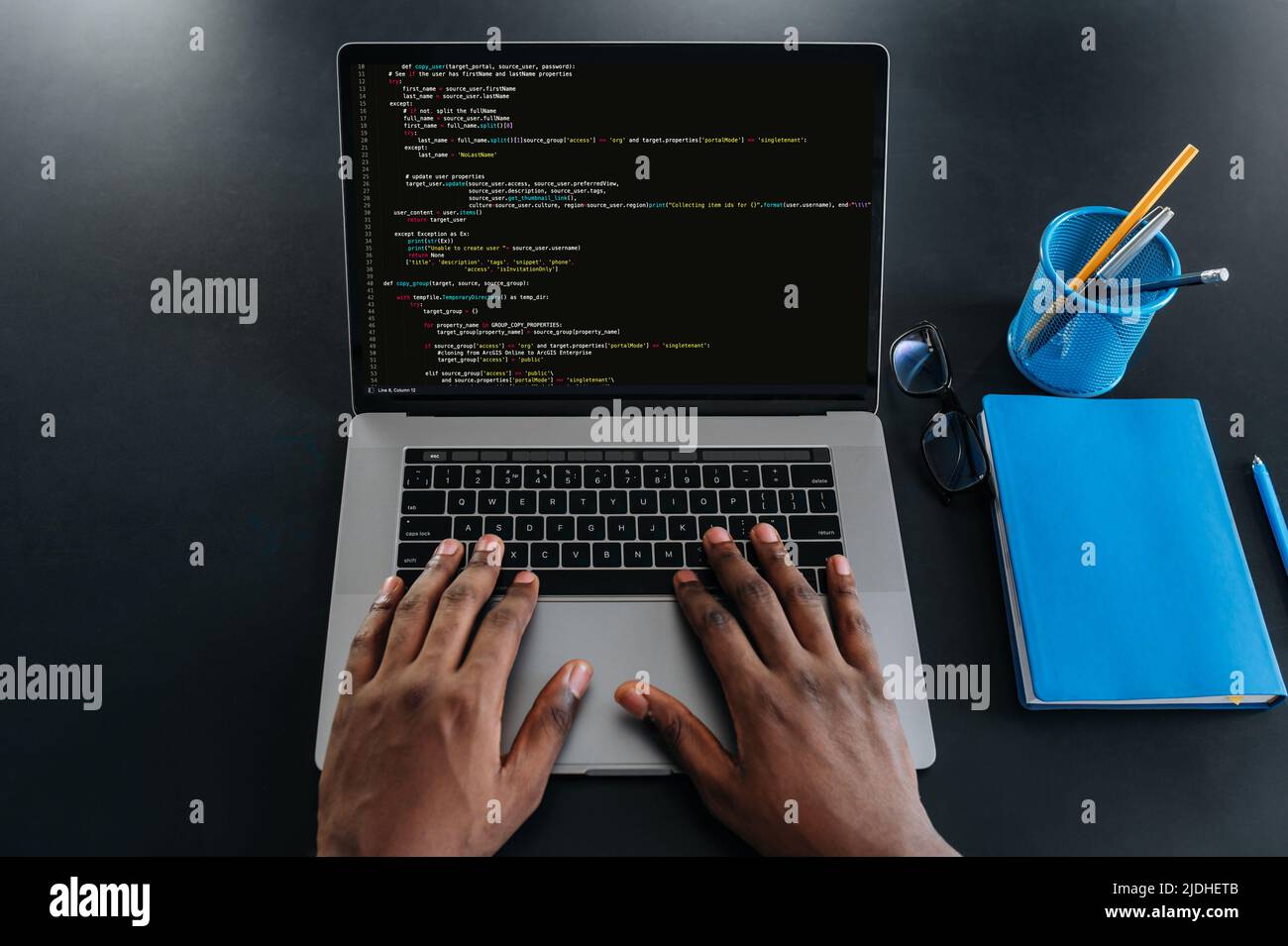 Top view of male african american hands on a laptop keyboard, IT specialist, programmer, sits in a modern office, working on the development of a website, application, writing codes and data code Stock Photo