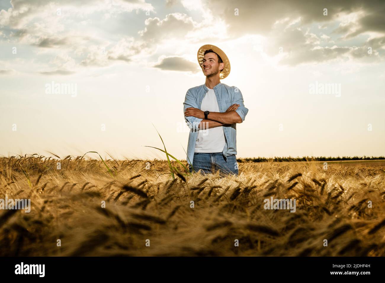 Happy farmer is standing in his growing barley field. Stock Photo