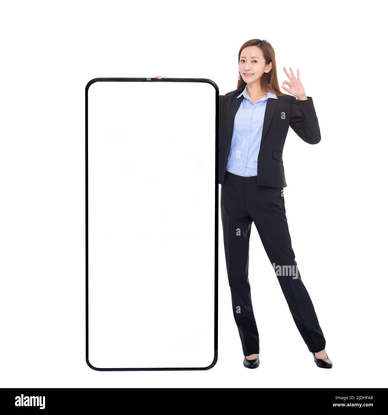 Business woman leaning on huge cellphone with blank white screen, showing ok gesture, recommending great new app or website for smart phone Stock Photo
