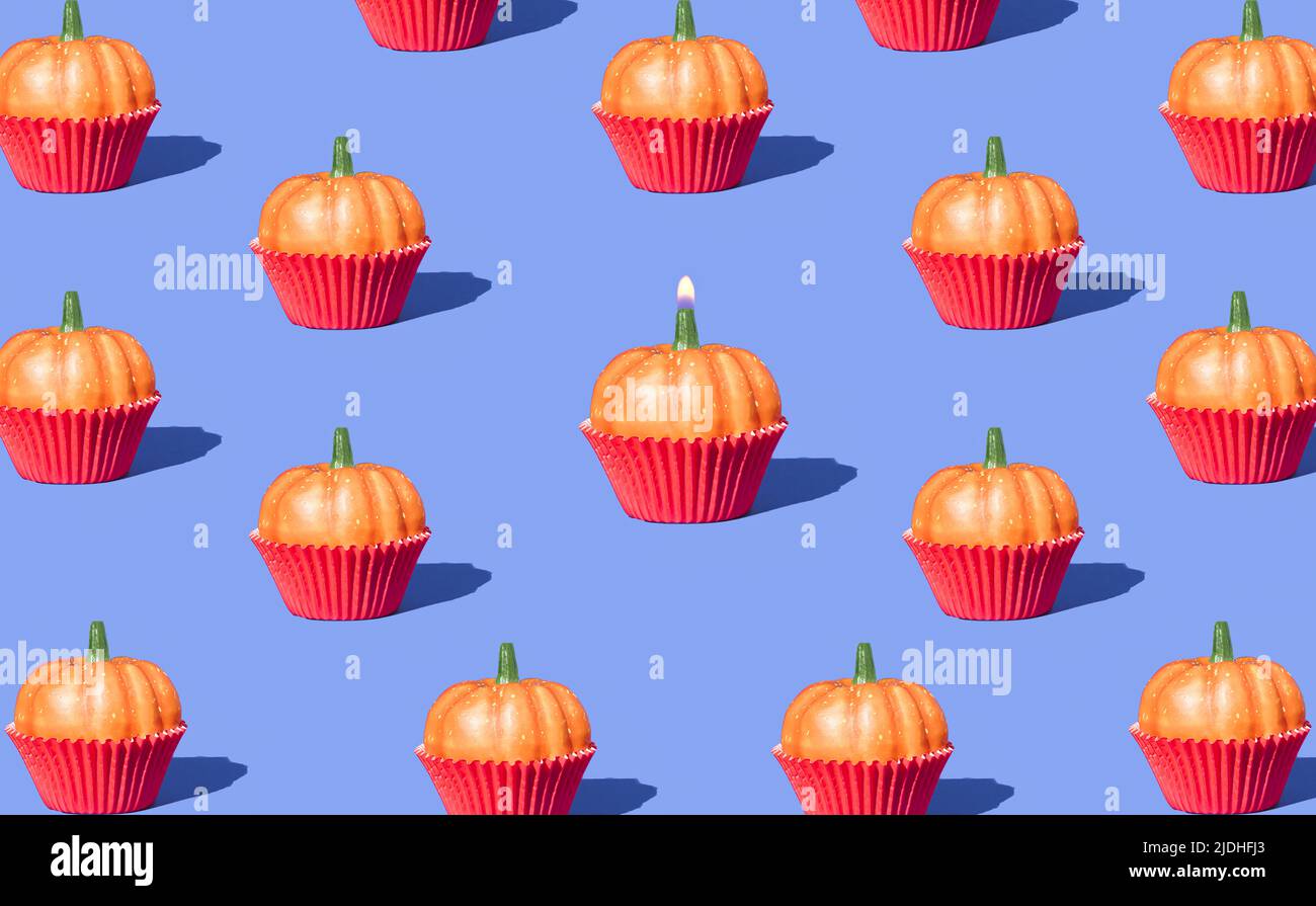 Autumn pattern with pumpkin capcakes and birthday candle on purple background. Creative holiday party background. Halloween minimal backdrop. Stock Photo