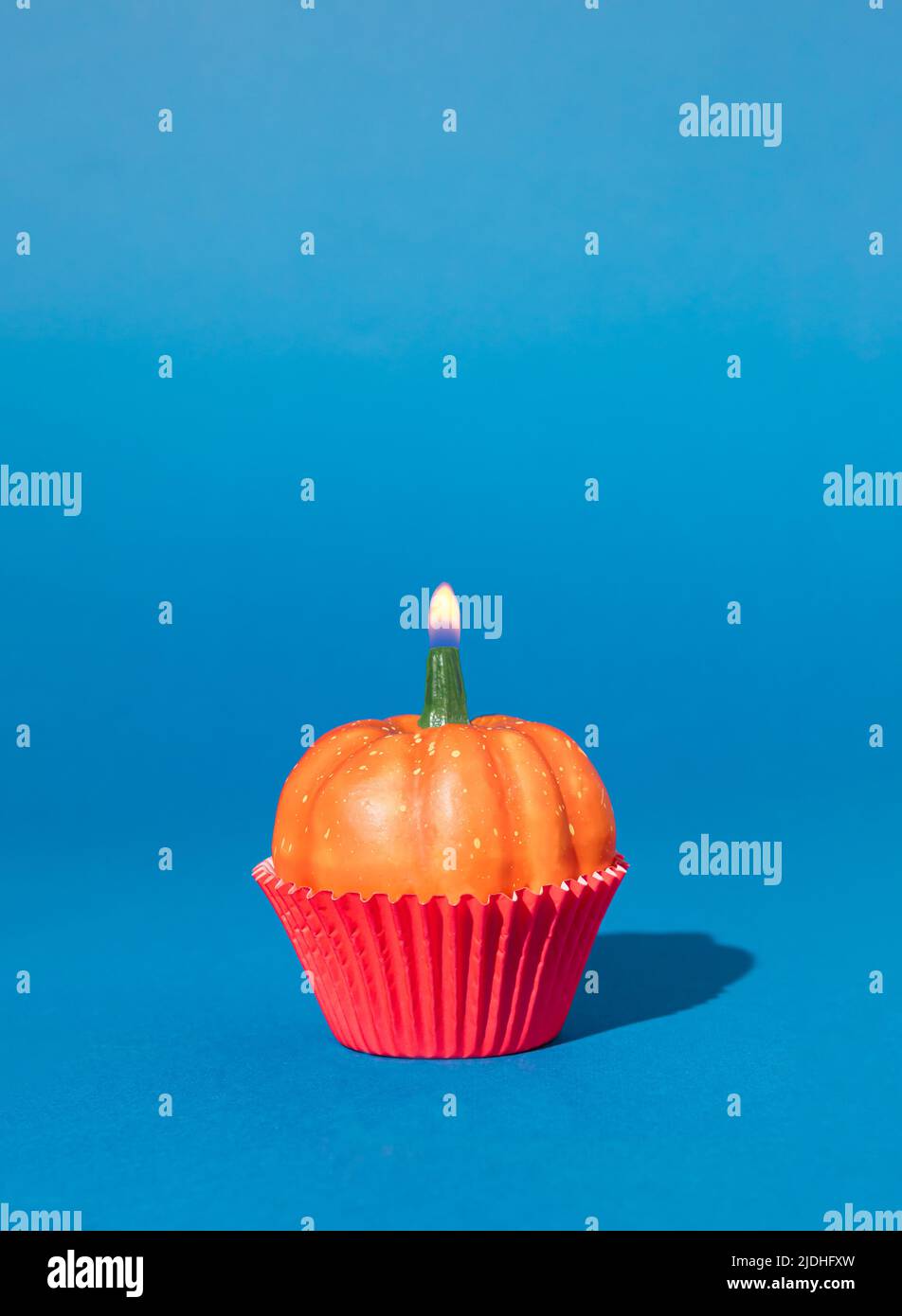 Halloween minimal concept with pumpkin and birthday candle. Creative holiday party background. Stock Photo