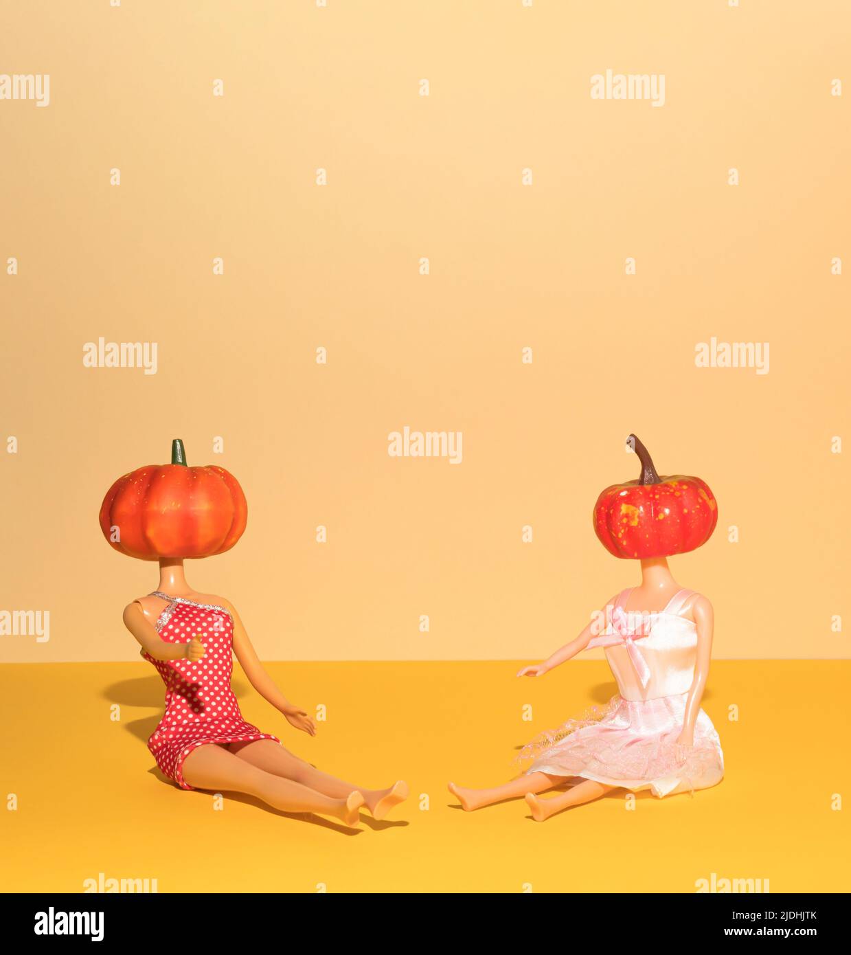 Halloween funny concept made of girl dolls with pumpkins. Minimal