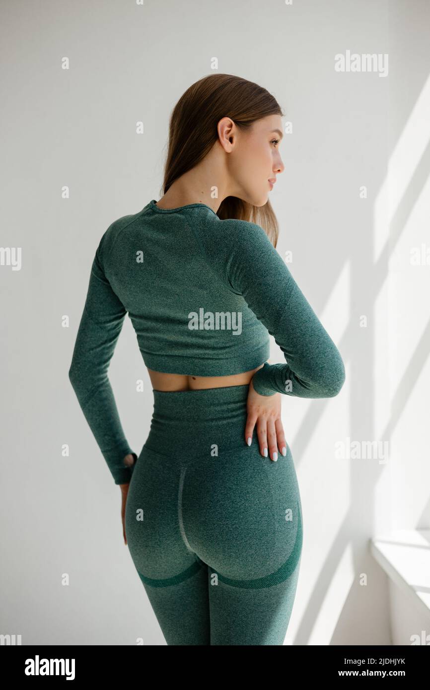 Beautiful sports girl in a green suit for fitness on a white background ...